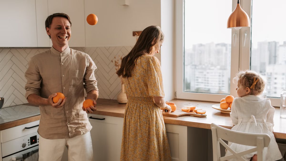 Family bonding in a bright kitchen, juggling oranges and sharing laughter.